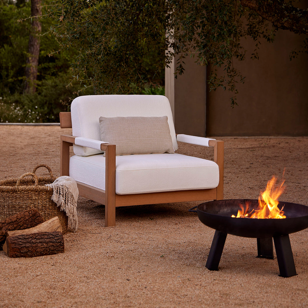 White linen chair with a light wooden frame, set against a natural sandy background. Cozy and minimalist design.