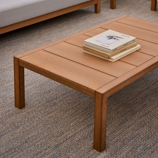 Light wood coffee table with a smooth, slatted surface, set on a textured neutral rug. Perfect for modern decor.