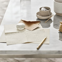 "Elegant neutral tones and soft textures with patterned papers and minimalist ceramic items on a marble surface."