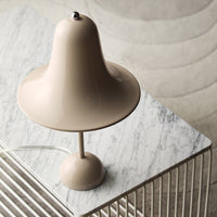 Minimalist beige lamp with a smooth, bell-shaped shade atop a marble surface, featuring subtle textures and soft tones.