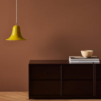 "Yellow pendant light above dark brown dresser with neutral beige bowl and stacked books."