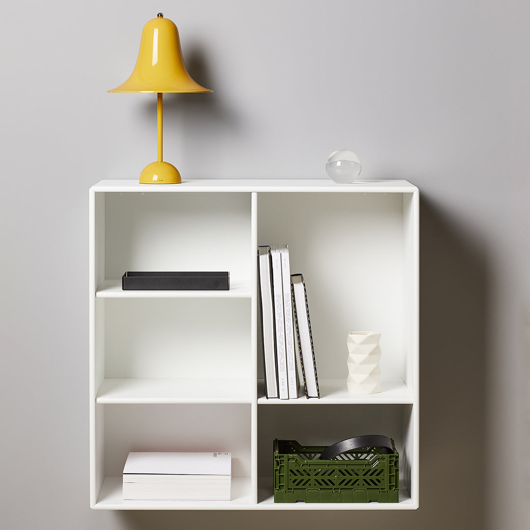 Modern white shelving unit with yellow lamp and green basket, featuring clean lines and minimal pattern.