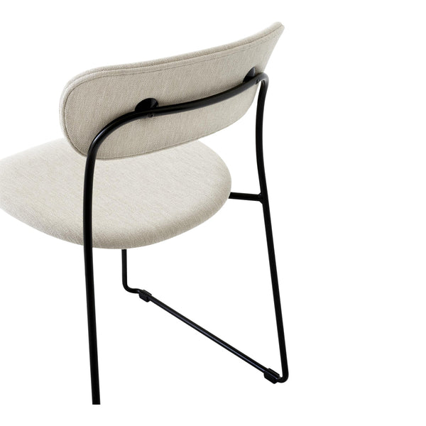Beige upholstered chair with minimalist black metal frame and sleek lines, showcasing a modern and stylish design.