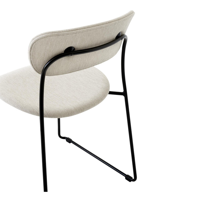 Beige upholstered chair with minimalist black metal frame and sleek lines, showcasing a modern and stylish design.