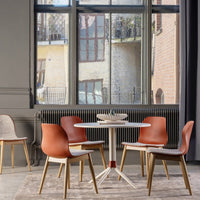 Mid-century modern dining set features warm terracotta chairs, light gray upholstery, and a sleek round white table.