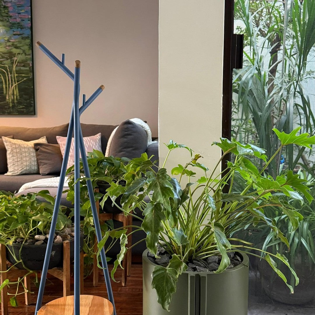 "Modern blue plant stand with natural wood base, surrounded by vibrant green foliage in a stylish indoor setting."