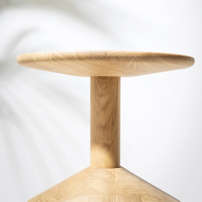 Light oak wood stool with a smooth round top and geometric base, showcasing natural grain patterns.