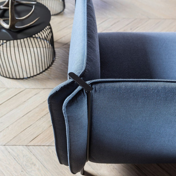 Sleek blue and gray velvet sofa detail with smooth textures and modern lines against a light wooden floor.