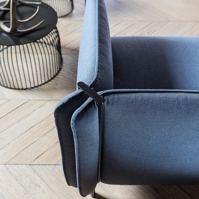 Sleek blue and gray velvet sofa detail with smooth textures and modern lines against a light wooden floor.