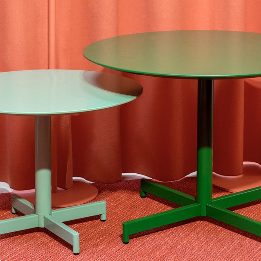 Green and mint round tables against coral curtains and a textured red floor. Modern and vibrant color palette.