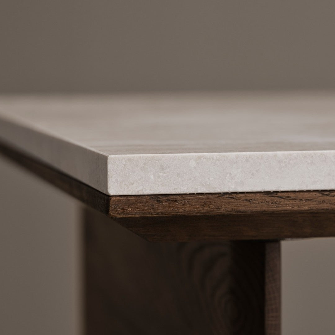 Close-up of a sleek white stone tabletop with a smooth finish, set against rich brown wooden edges.