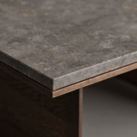 Close-up of a textured gray stone countertop with warm brown wood edges, showcasing a modern and natural pattern.