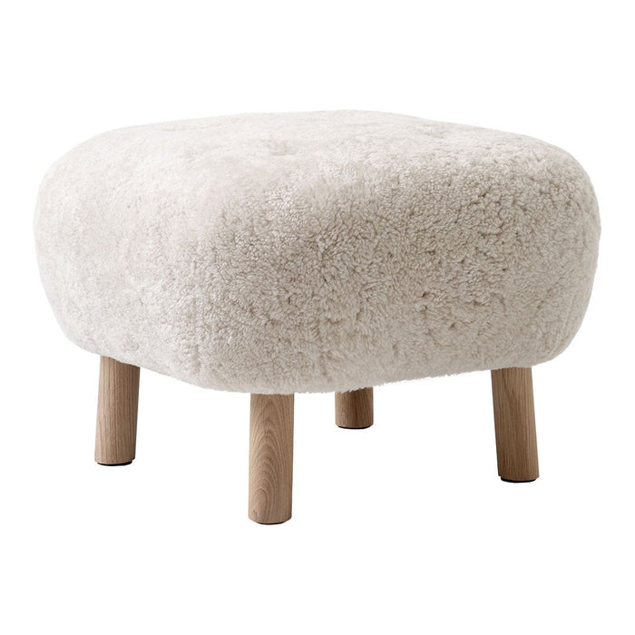 Cream-colored textured ottoman with rounded edges and light wooden legs. Ideal for cozy living spaces.