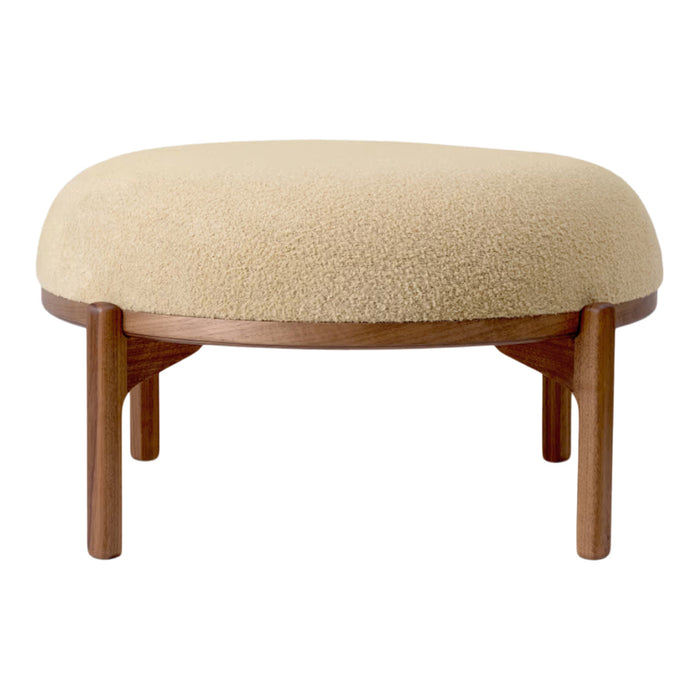 Beige boucle upholstered ottoman with wooden legs, featuring a round shape and soft texture for modern decor.