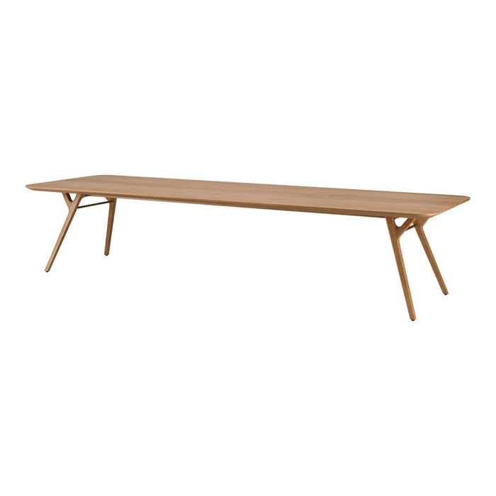 Lightly stained natural wood dining table with smooth, minimalist design and unique angled legs.