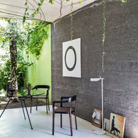 Chic interior featuring green walls, dark gray textures, and minimalist black chairs with wooden accents, creating a modern vibe.