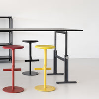 Colorful bar stools in red, yellow, black, and gray with sleek, modern designs on a minimalist background.