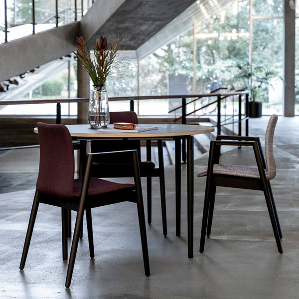Modern dining table with burgundy and light gray patterned chairs, contrasted by sleek black legs in a chic interior setting.