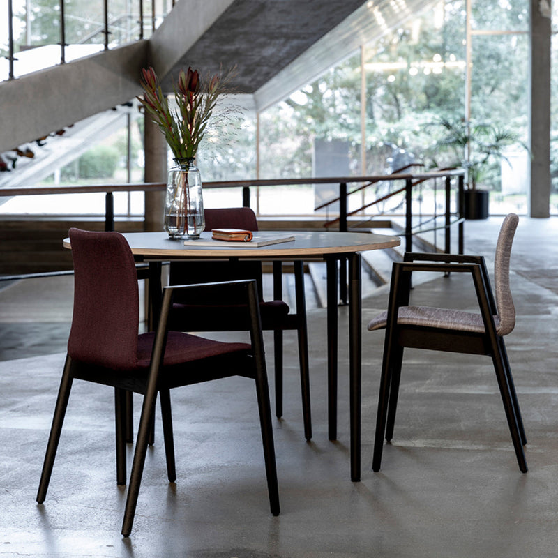 Modern dining table with burgundy and light gray patterned chairs, contrasted by sleek black legs in a chic interior setting.