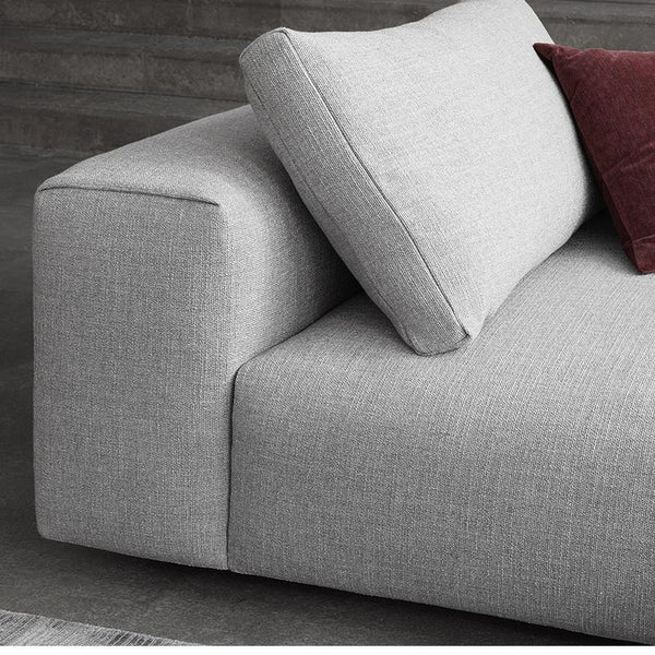 Light gray sofa with a textured fabric and a deep burgundy pillow, showcasing a modern minimalist design.