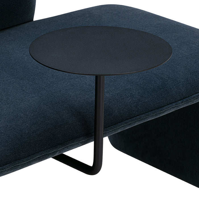 Black metal side table on dark blue upholstery, showcasing a modern and minimalist design.