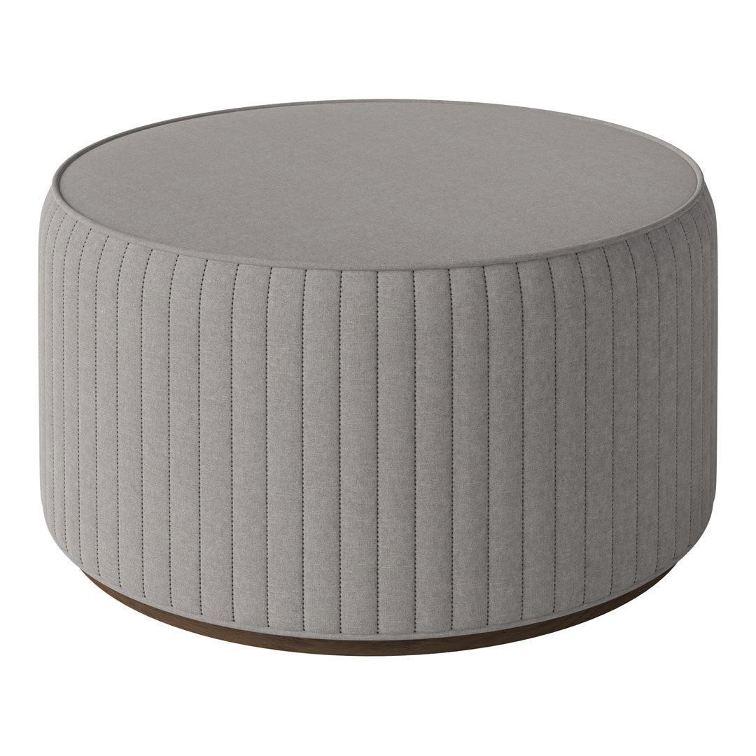 Round grey upholstered ottoman with vertical ribbed pattern and a wooden base. Ideal for modern décor.