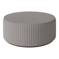 Round grey ottoman with vertical ribbed texture and a smooth top, perfect for modern decor.