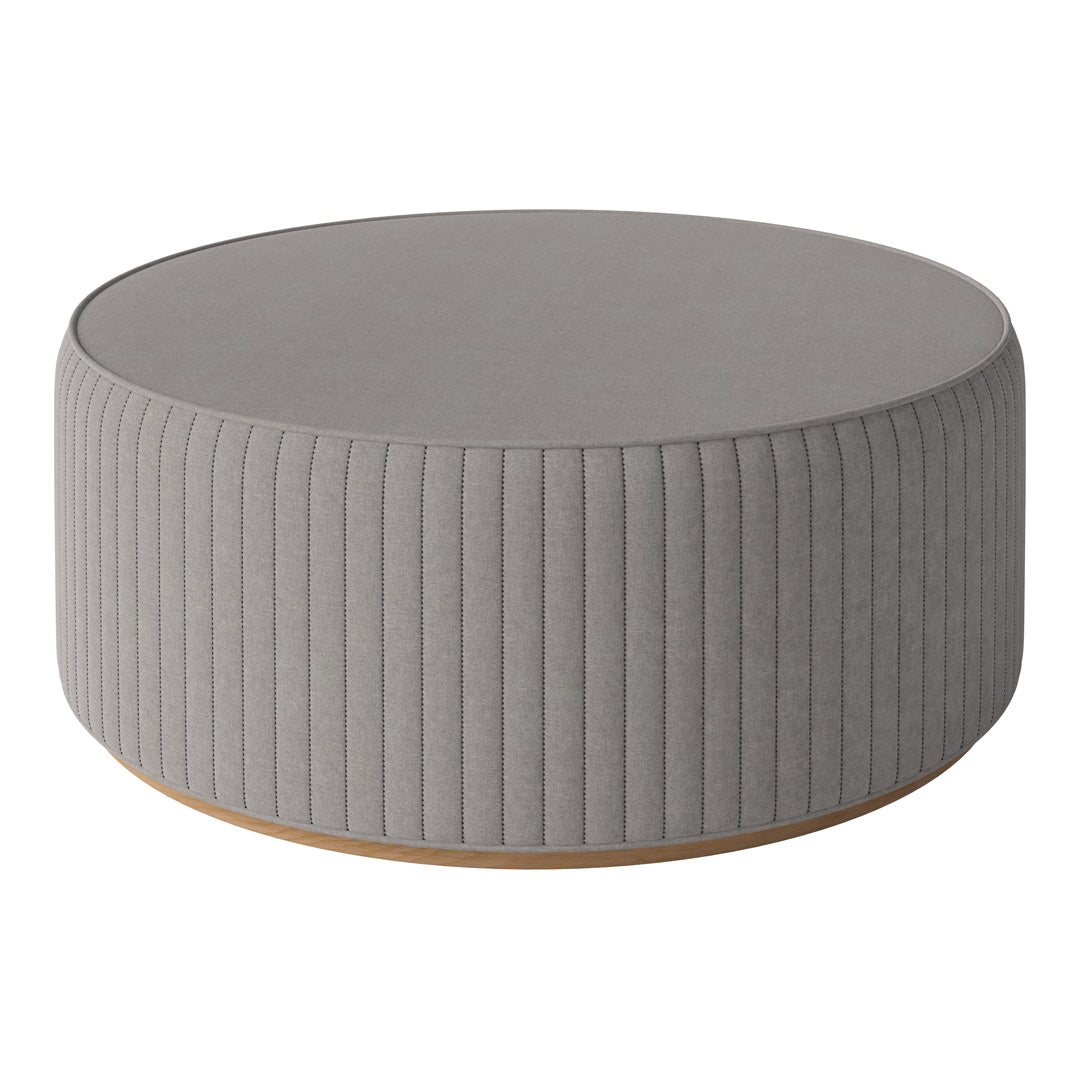 Round gray ottoman with subtle vertical ribbed pattern and a smooth top, featuring a light wood base.
