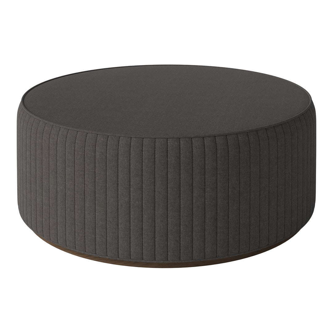 Round ottoman in dark gray with vertical ribbed pattern and smooth top surface. Modern and stylish accent piece.