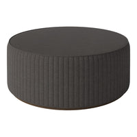 Round ottoman in dark gray with vertical ribbed pattern and smooth top surface. Modern and stylish accent piece.
