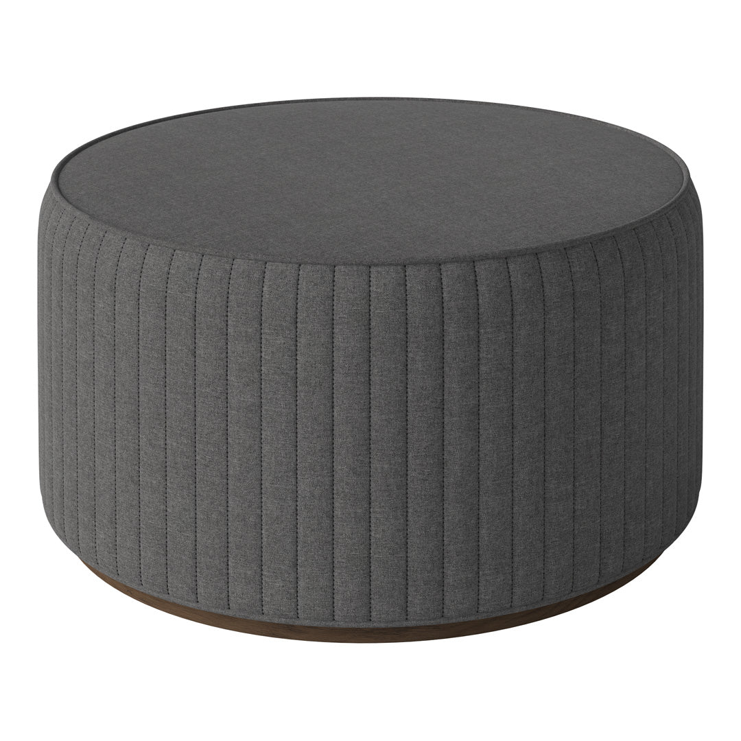 Round gray ottoman featuring vertical ribbed detailing and a smooth top surface, ideal for modern decor.
