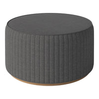 Round gray upholstered ottoman with vertical ribbed texture and wooden base. Stylish and modern furniture piece.