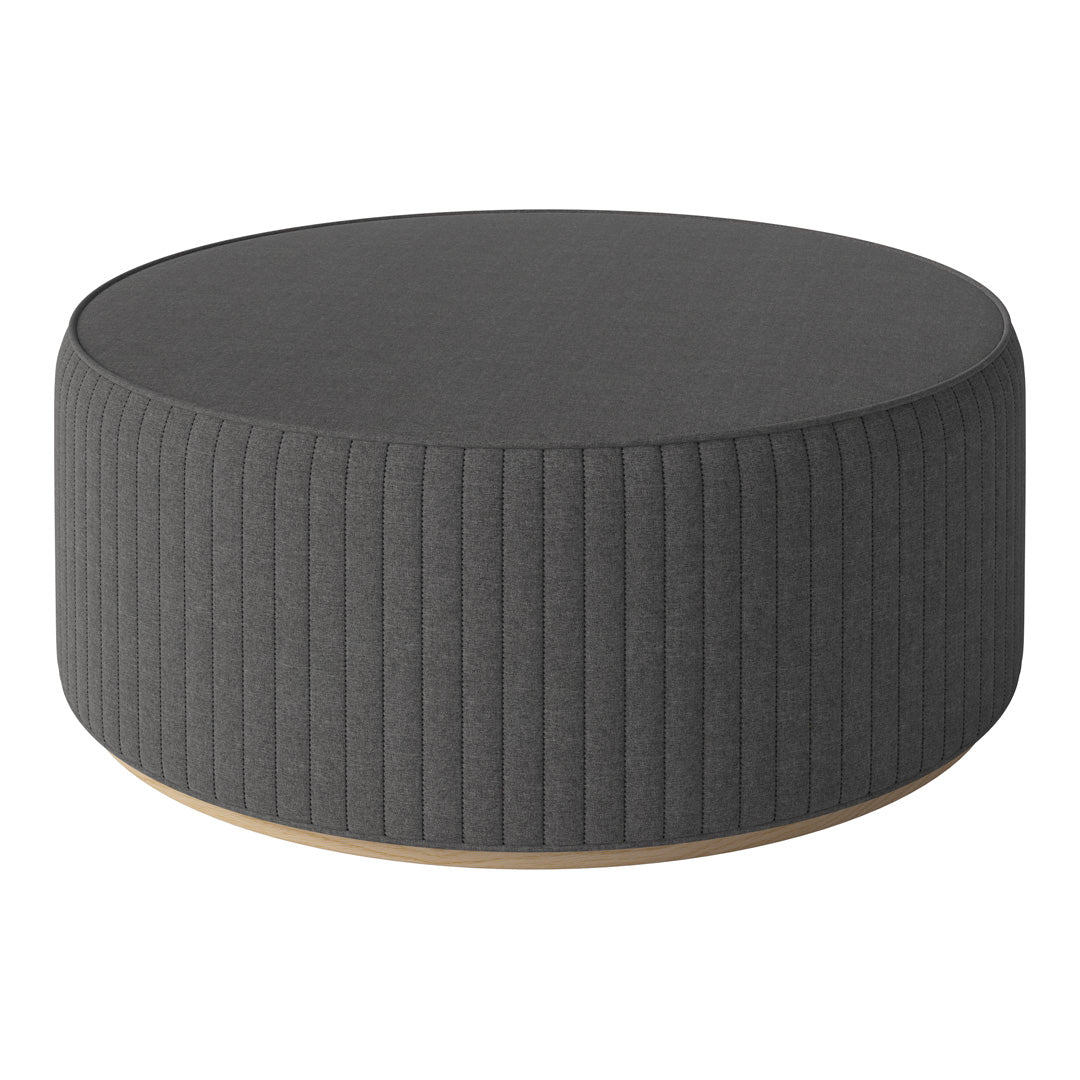 Dark gray round ottoman with vertical ribbed fabric pattern and natural wood base.