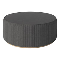 Dark gray round ottoman with vertical ribbed fabric pattern and natural wood base.
