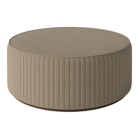 Beige round ottoman with textured ribbed fabric and a smooth top surface, ideal for modern decor.