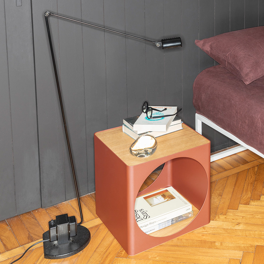 Copper and black modern lamp beside a round, wooden top side table with a terracotta base. Elegant interior design elements.