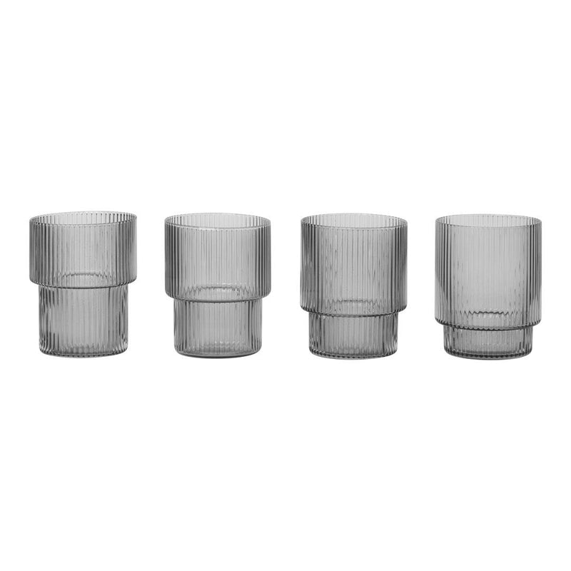 Set of four clear glass tumblers with vertical ribbed patterns and varying heights. Elegant and modern design.