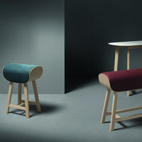 Modern wooden stools in teal and burgundy with a minimalist design, set against a muted gray backdrop.