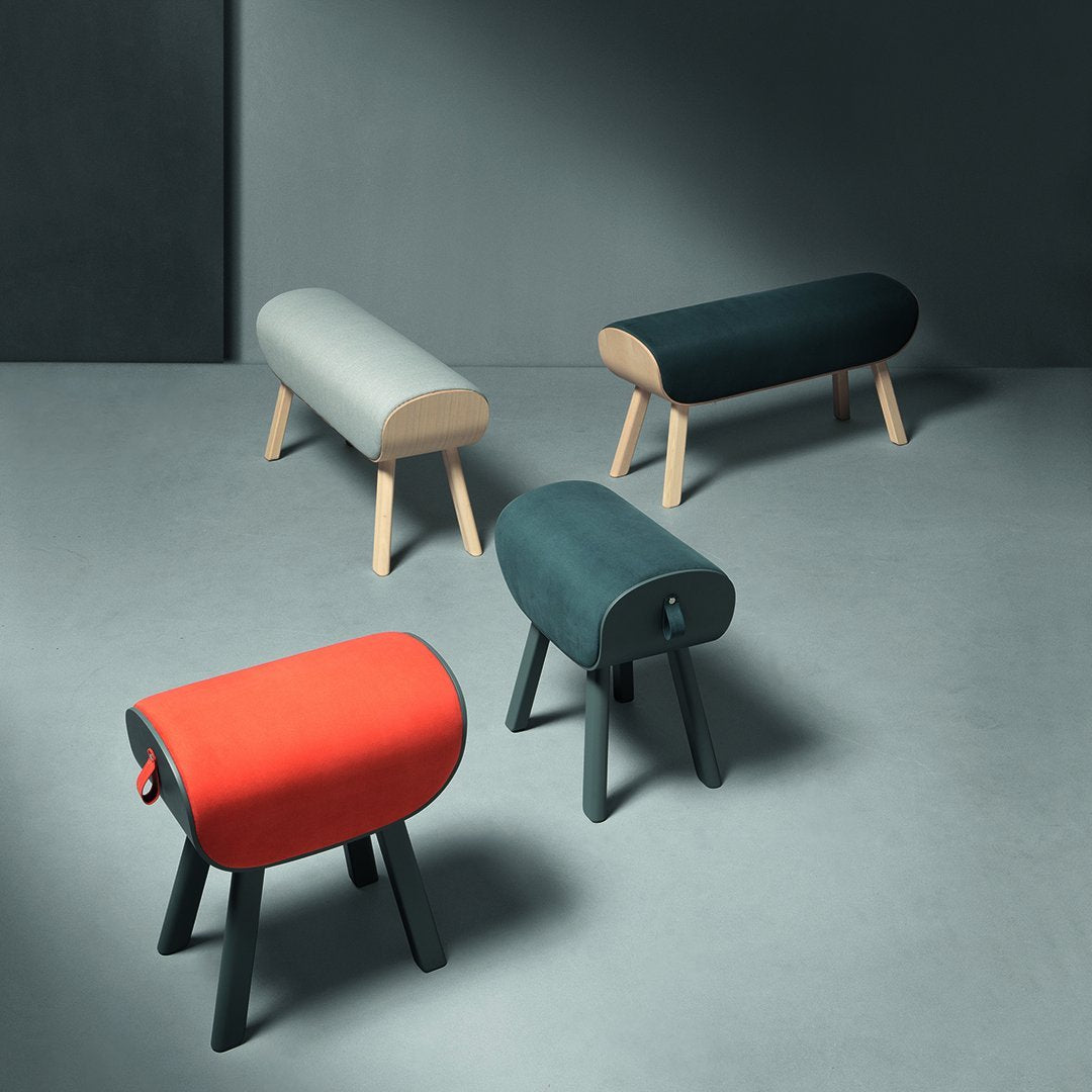 Colorful modern benches in gray, teal, black, and bright red with sleek wooden legs and rounded shapes.
