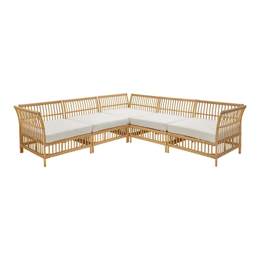 Natural bamboo corner sofa with cream cushions, featuring a sleek slatted design for a modern, airy look.