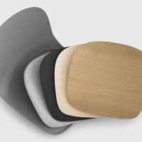 Stack of colorful seat cushions in graphite grey, soft grey, sleek black, and warm oak wood finishes.