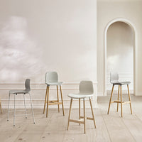 Set of modern bar stools in gray and light upholstery, featuring natural wooden legs on a clean, neutral backdrop.