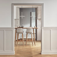 "Light gray bar stools with wood legs, beige walls, and natural wood herringbone flooring in a modern kitchen setting."