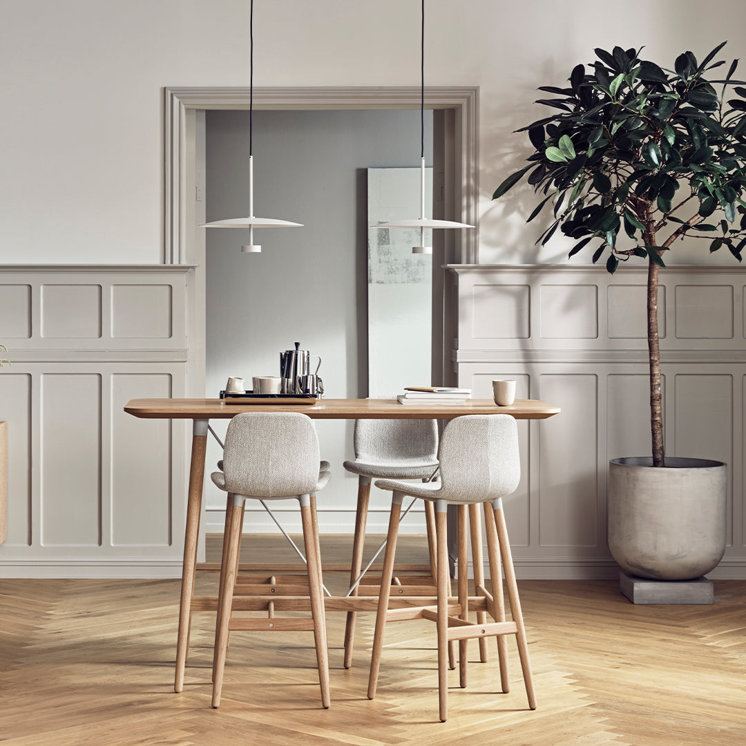 Modern bar stools with soft gray upholstery on light wood legs, paired with a natural wood tabletop in a neutral-toned setting.
