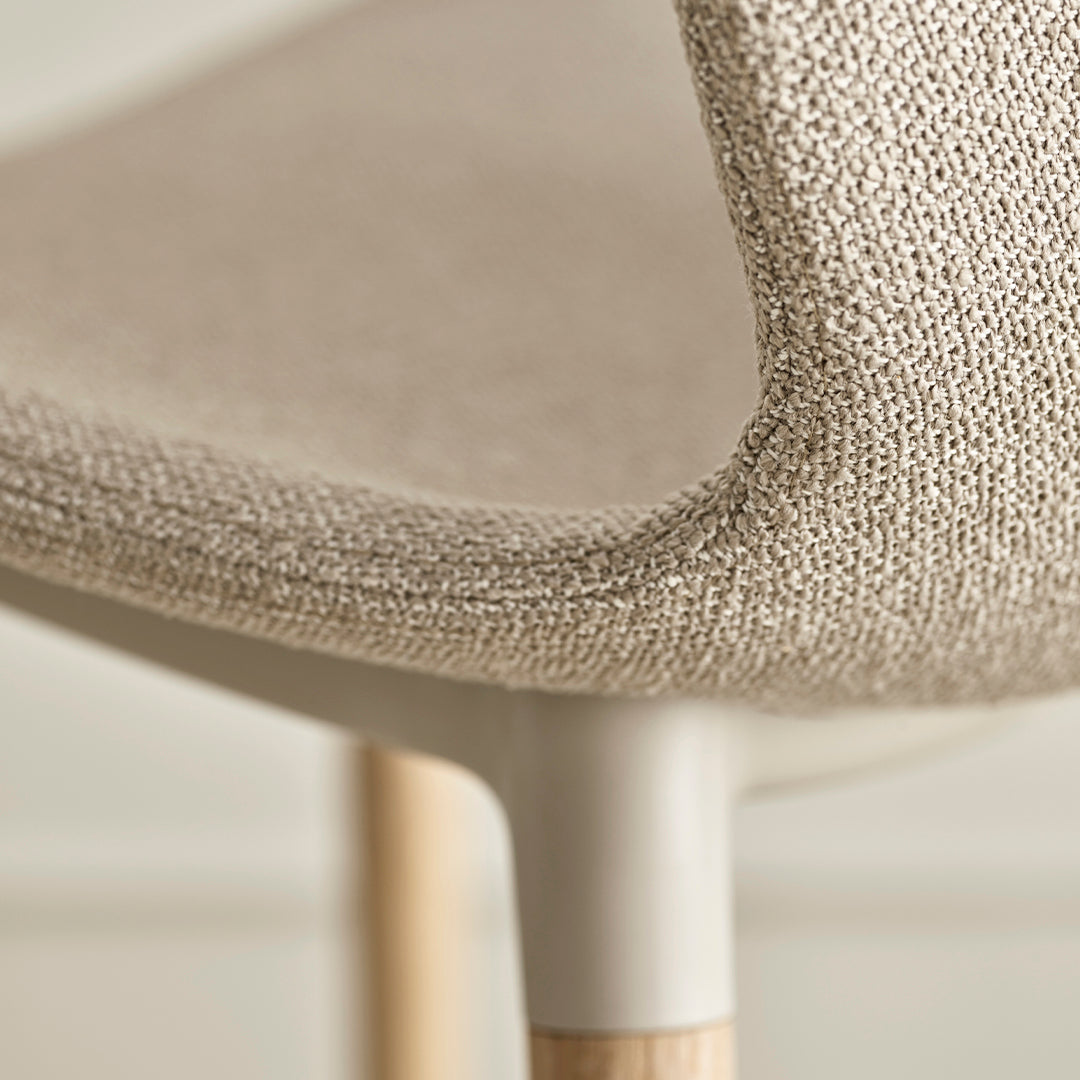 Beige textured upholstery with a subtle weave pattern, complemented by light wooden legs.