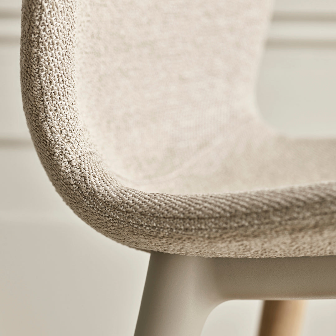 Beige textured chair upholstery with a smooth, neutral frame and natural wood accents.