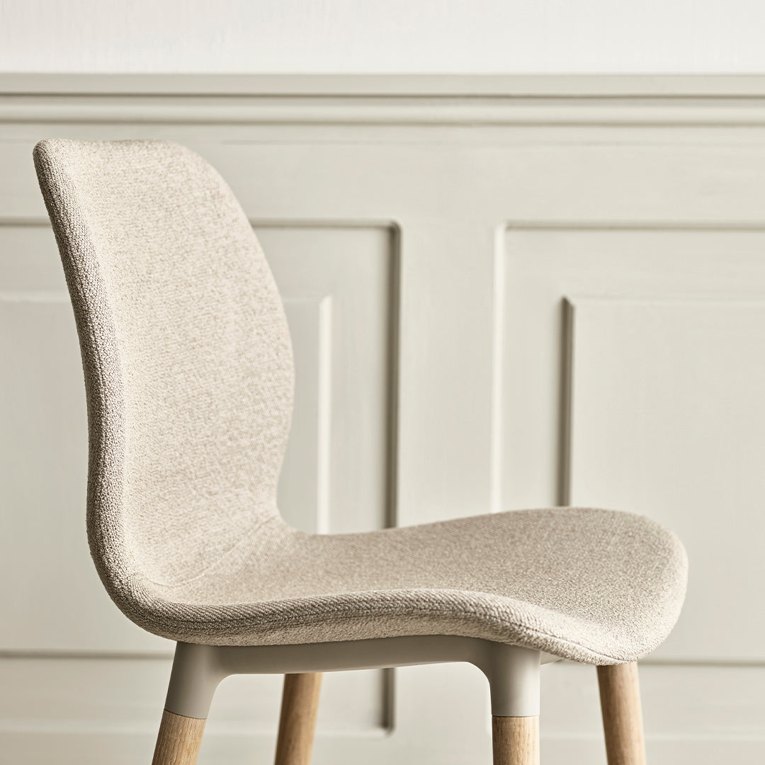 Beige textured chair with light wood legs against a soft, neutral wall. Perfect blend of modern and minimalist design.