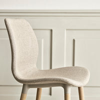 Beige textured chair with light wood legs against a soft, neutral wall. Perfect blend of modern and minimalist design.