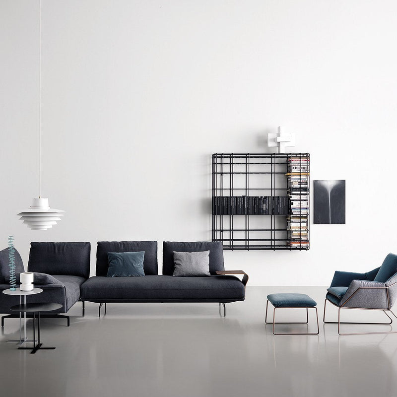 Modern living room featuring a dark gray sofa, teal accents, and a black geometric shelf against a white wall.