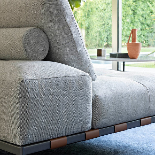 Light gray textured sofa with a cylindrical cushion, featuring a sleek black and brown frame. Modern, minimalist design.